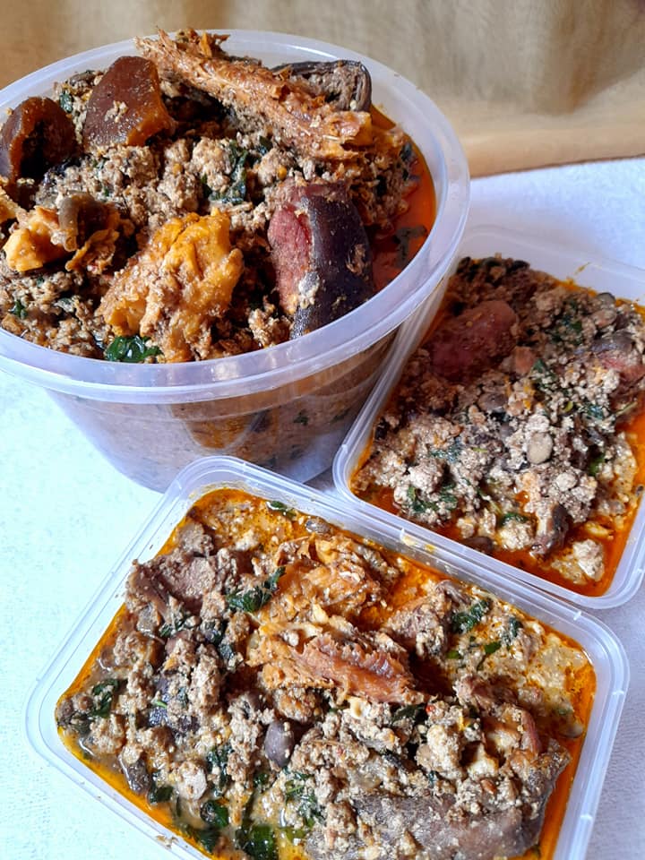 Containers of beniseed soup with greens and meat or fish